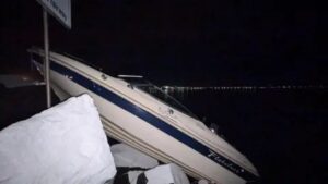 En motorbåt som har kraschat och strandat på stora stenblock i mörkret.